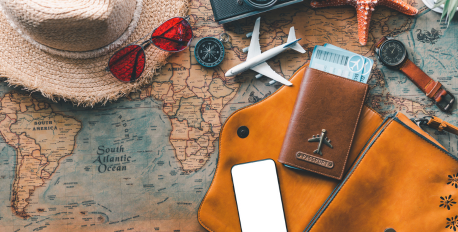 Travel essentials including a passport, straw hat, and sunglasses arranged on a vintage world map.