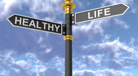 Street sign with Healthy and Life pointing in opposite directions against a blue sky.