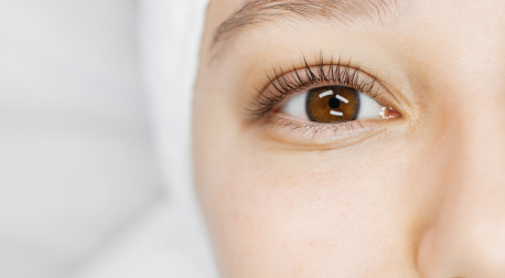 Close-up of a healthy, clear brown eye with long eyelashes on a bright background
