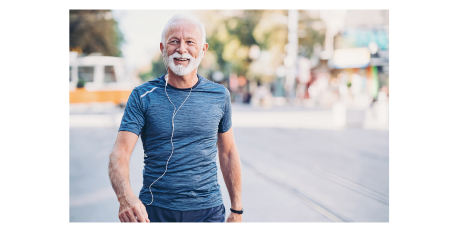 Smiling senior man in blue athletic shirt jogging outdoors with earphones.