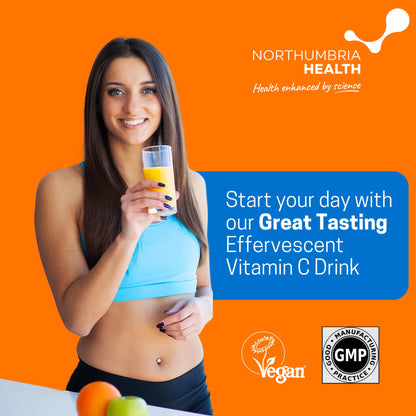 Smiling woman holding a glass of orange effervescent Vitamin C drink on an orange background.