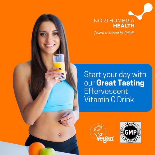 Smiling woman holding a glass of orange effervescent Vitamin C drink on an orange background.