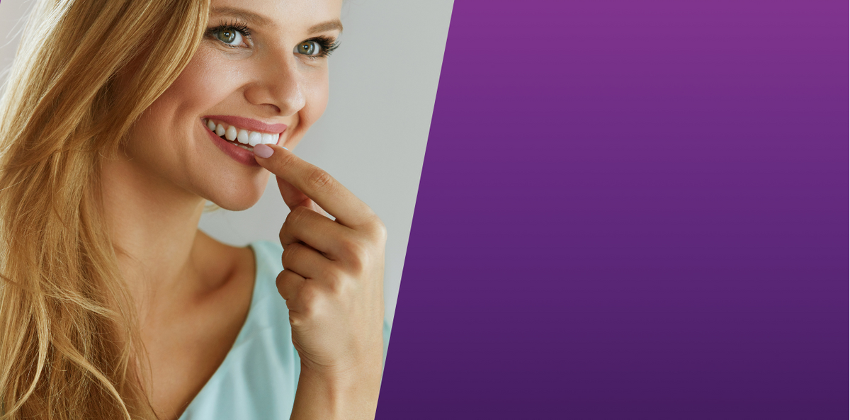 Smiling blonde woman showing her bright white teeth on a purple background.