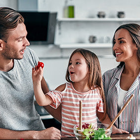 Family of three in a kitchen preparing food together