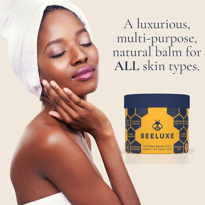 Beeluxe natural skin balm jar next to a woman with glowing skin wearing a hair towel.